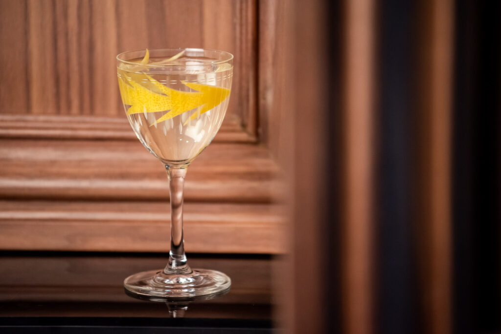 Classic martini cocktail with a lemon garnish against a wood backdrop