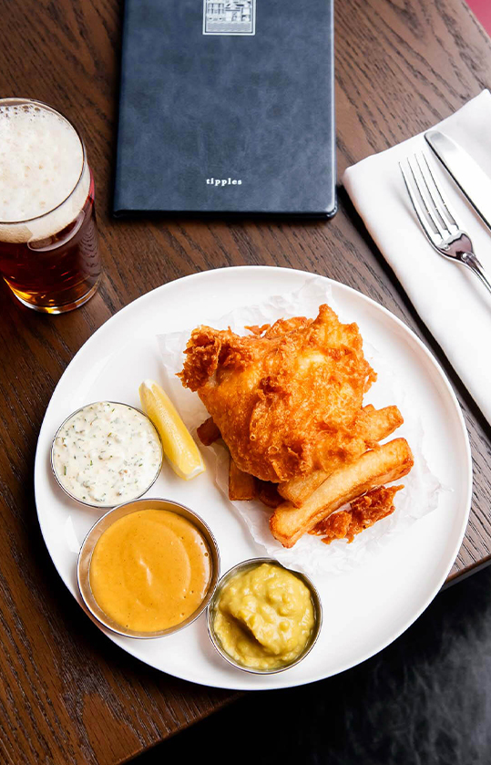 Overhead shot of Hake & Chips with a beer on a dark tabletop